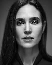 A black and white studio portrait of actress Jennifer Connelly, looking directly at the camera with a serious expression.